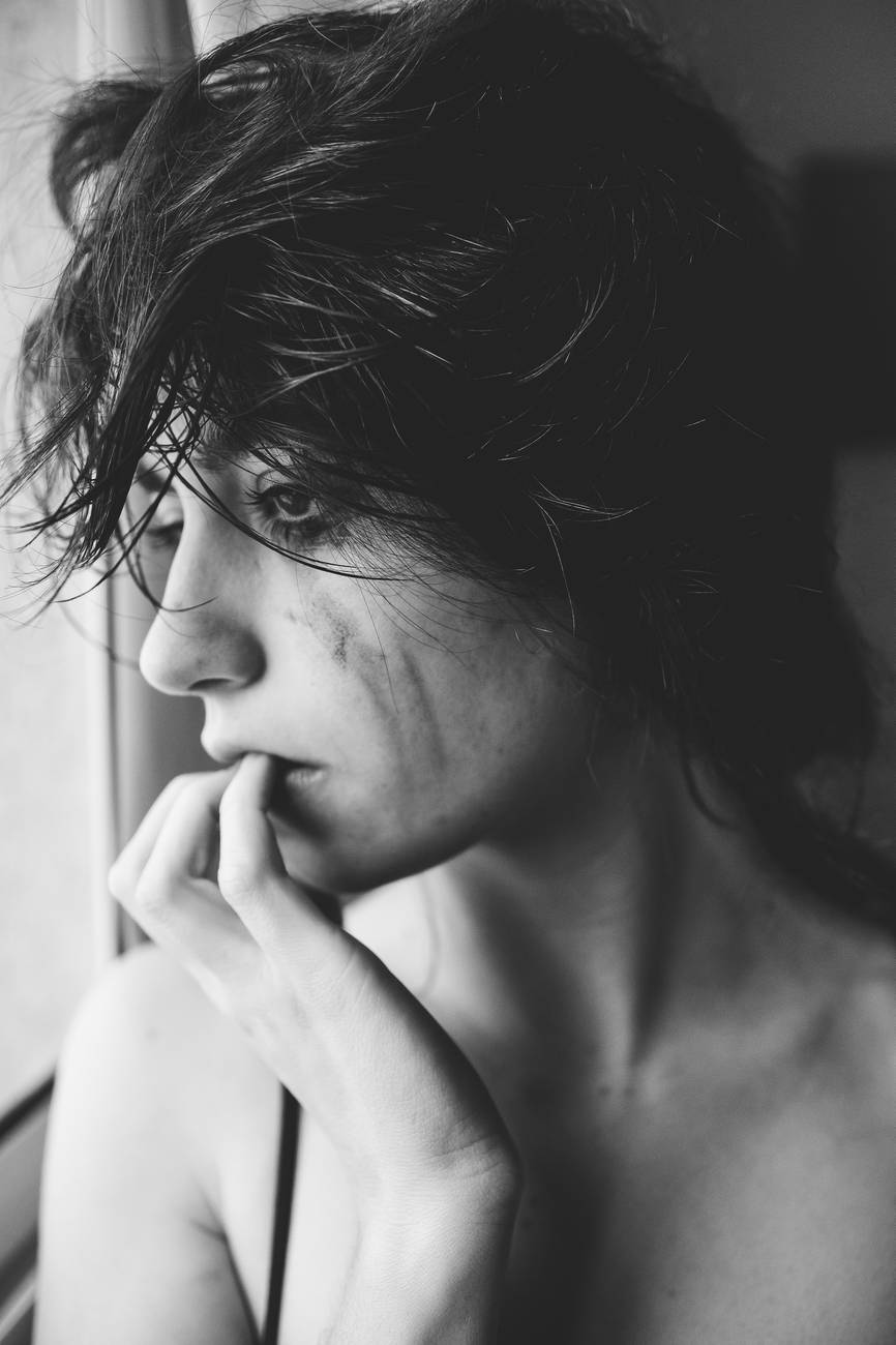 grayscale photography of woman looking out a window